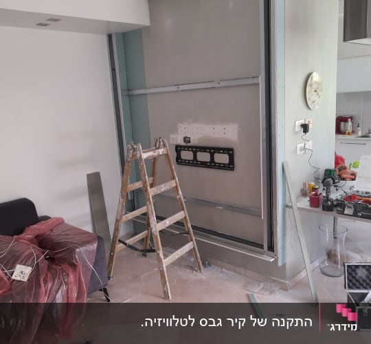 בניית נישת גבס לטלוויזיה בסלון במהלך תהליך העבודה